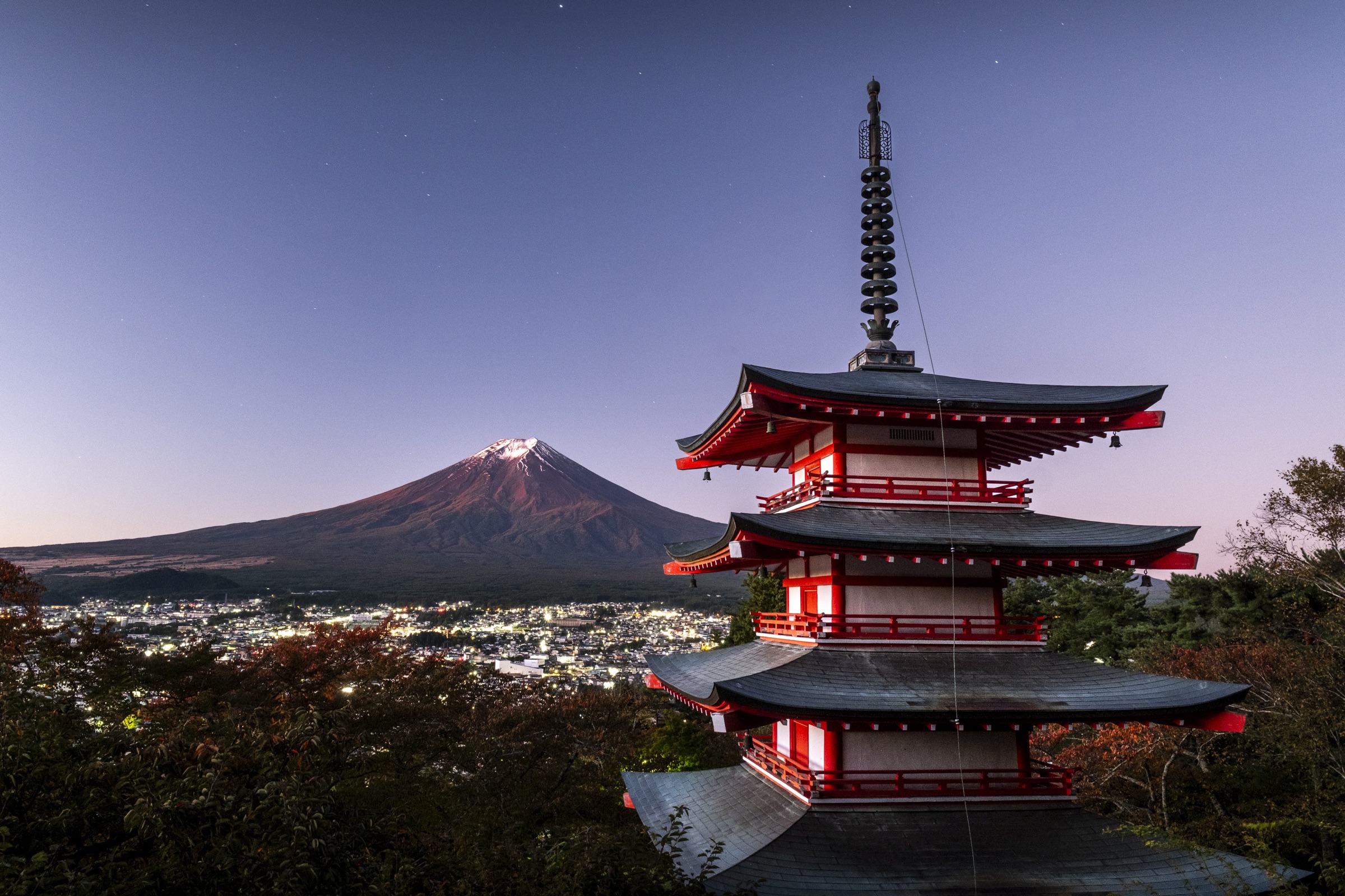A red pagoda overlooking Mount Fuji at dusk in Japan.