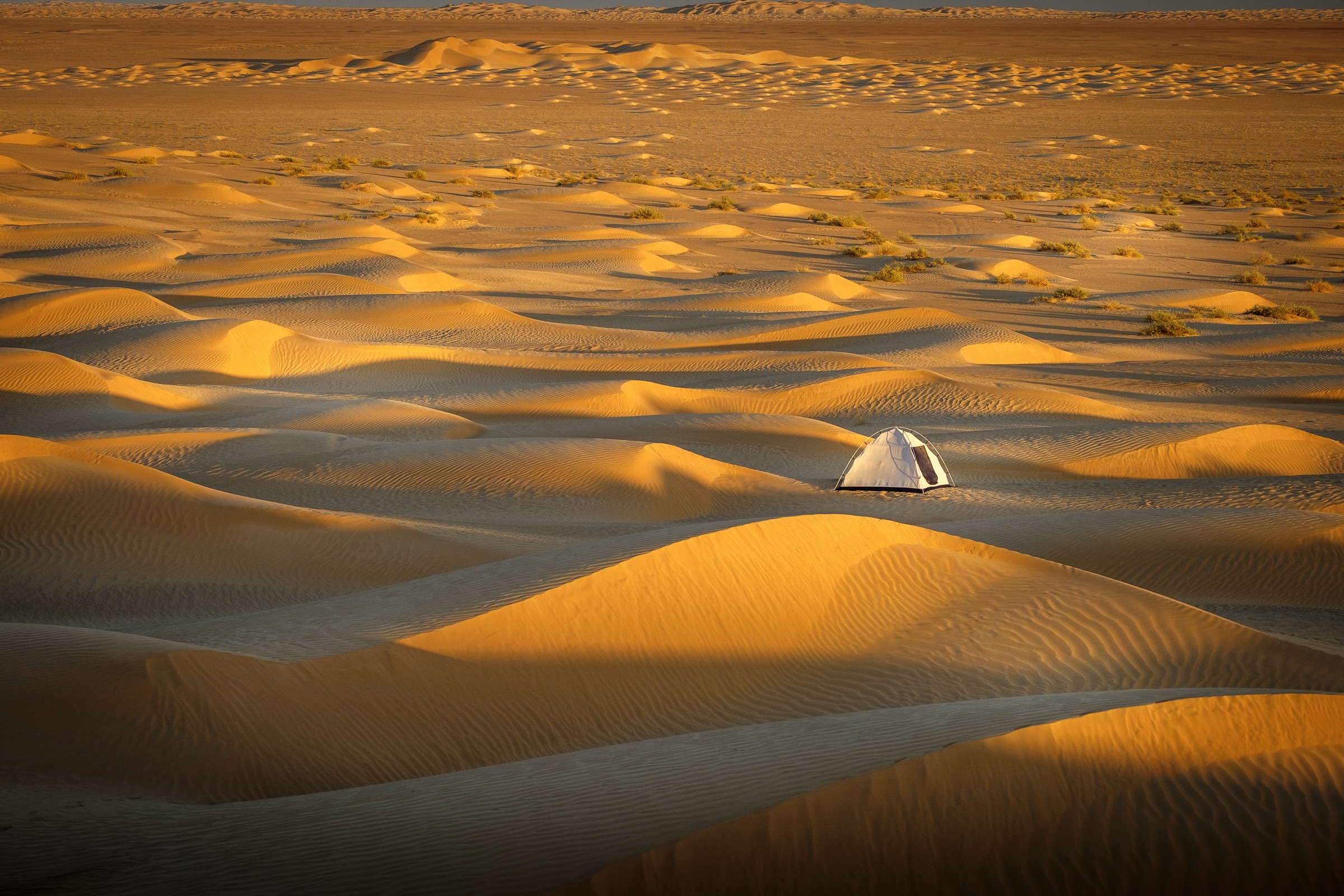 A small tent among golden sand dunes in Oman.