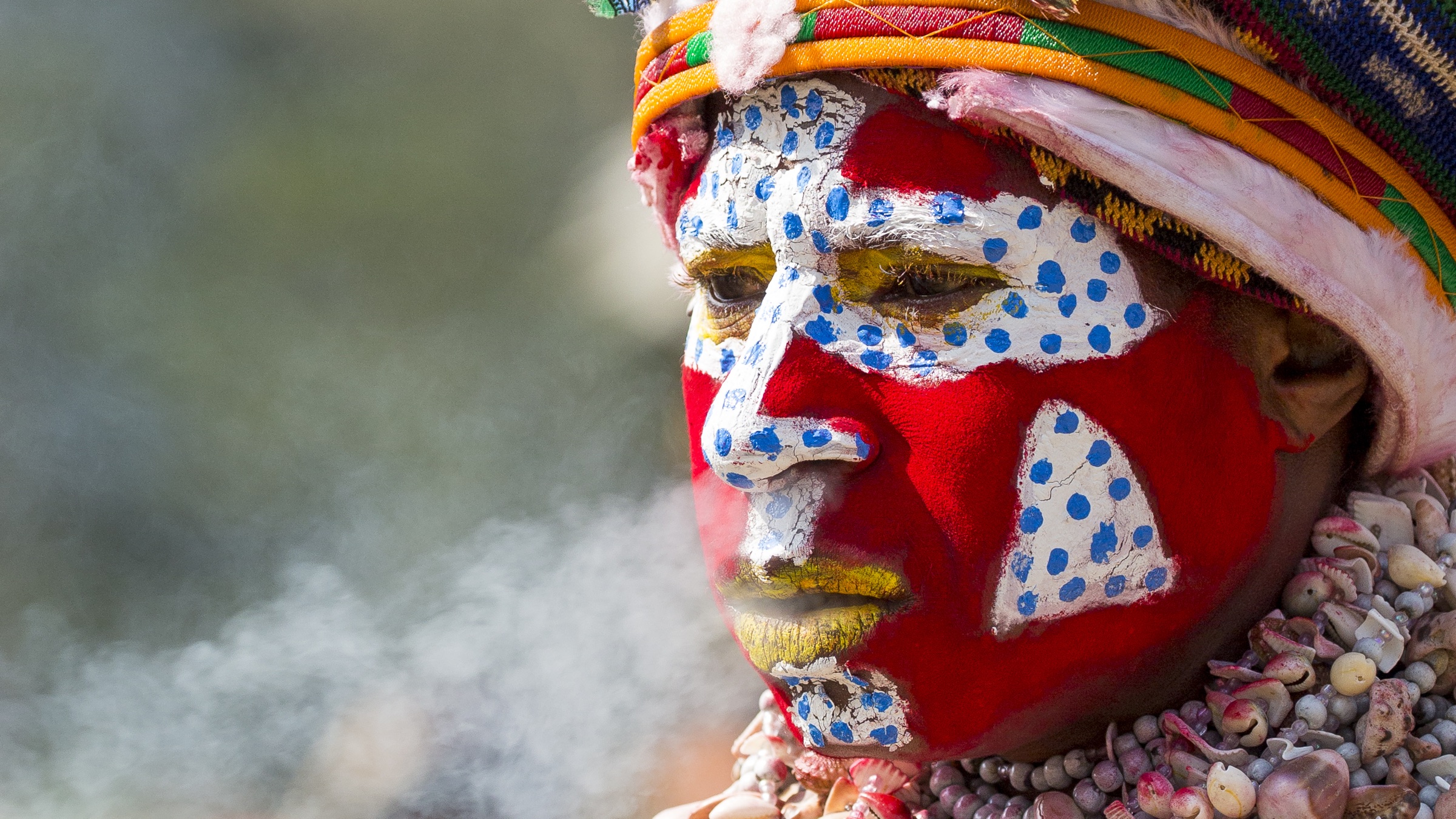 Portrait of a person wearing colourful face paint and an elaborate headdress in Papua New Guinea.