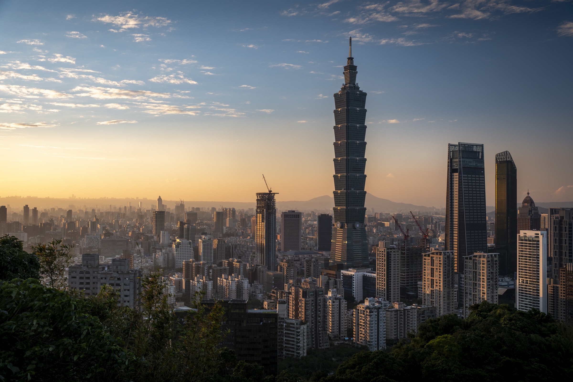 Taipei 101 rising above the city skyline at sunset.